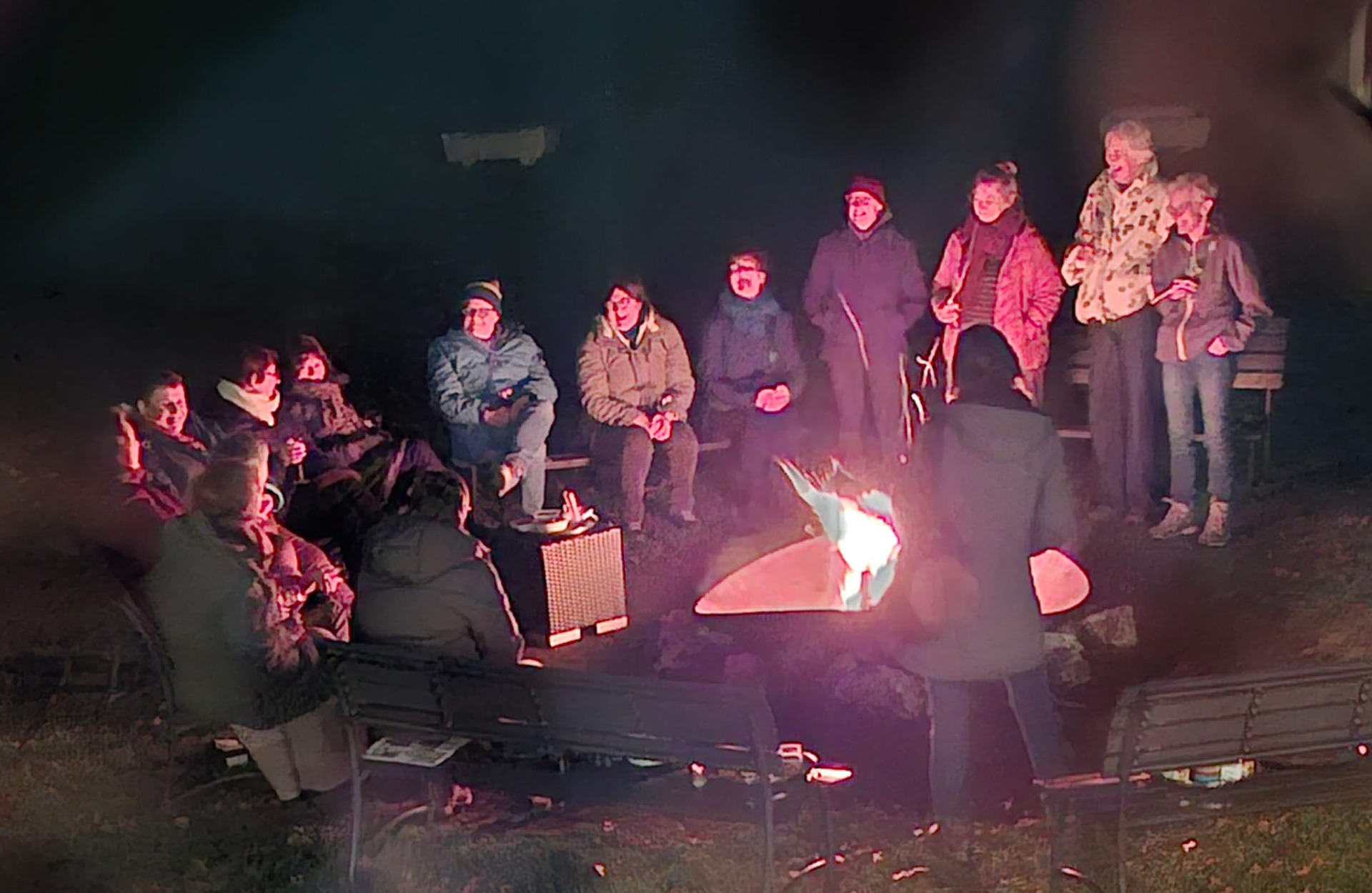 Groep mensen rond kampvuur.
